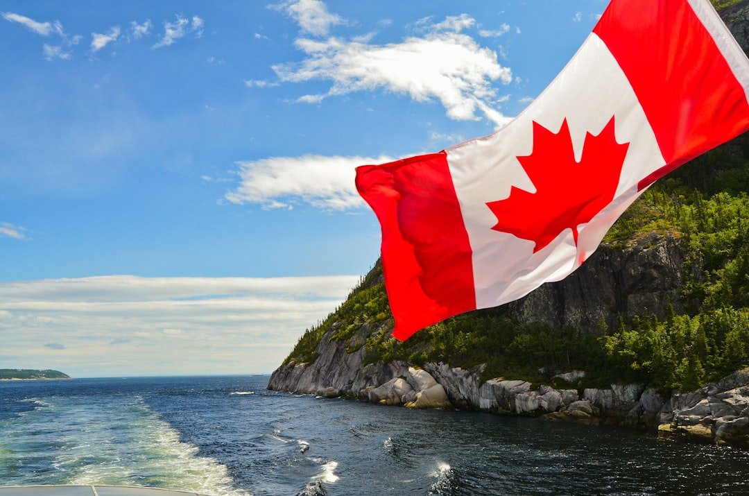 red-and-white-flag-on-rock-formation-near-body-of-water-during-daytime-mjfbzrgeqec